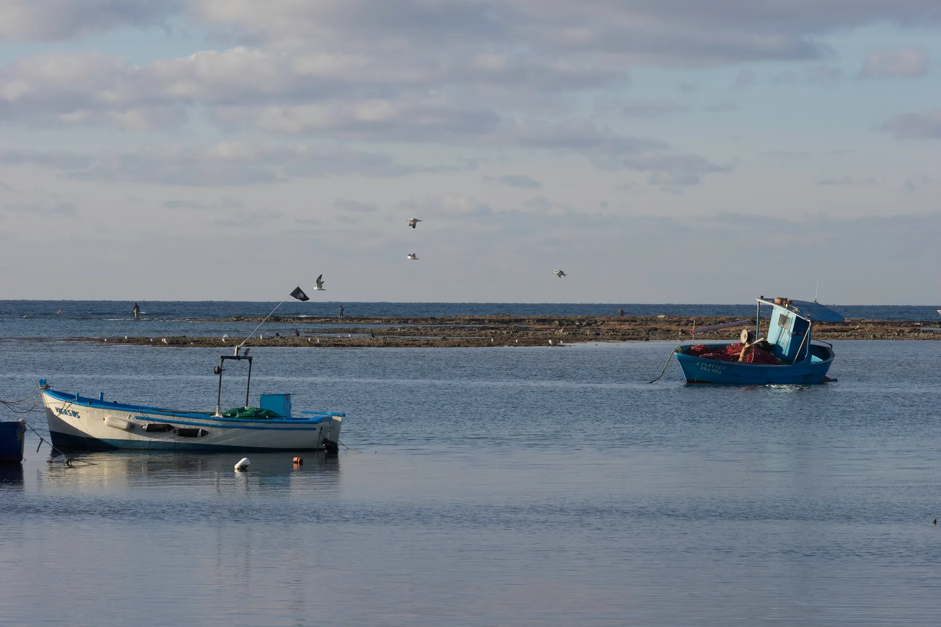 Two small boats docked on calm waters in Porto Cesareo, Puglia.